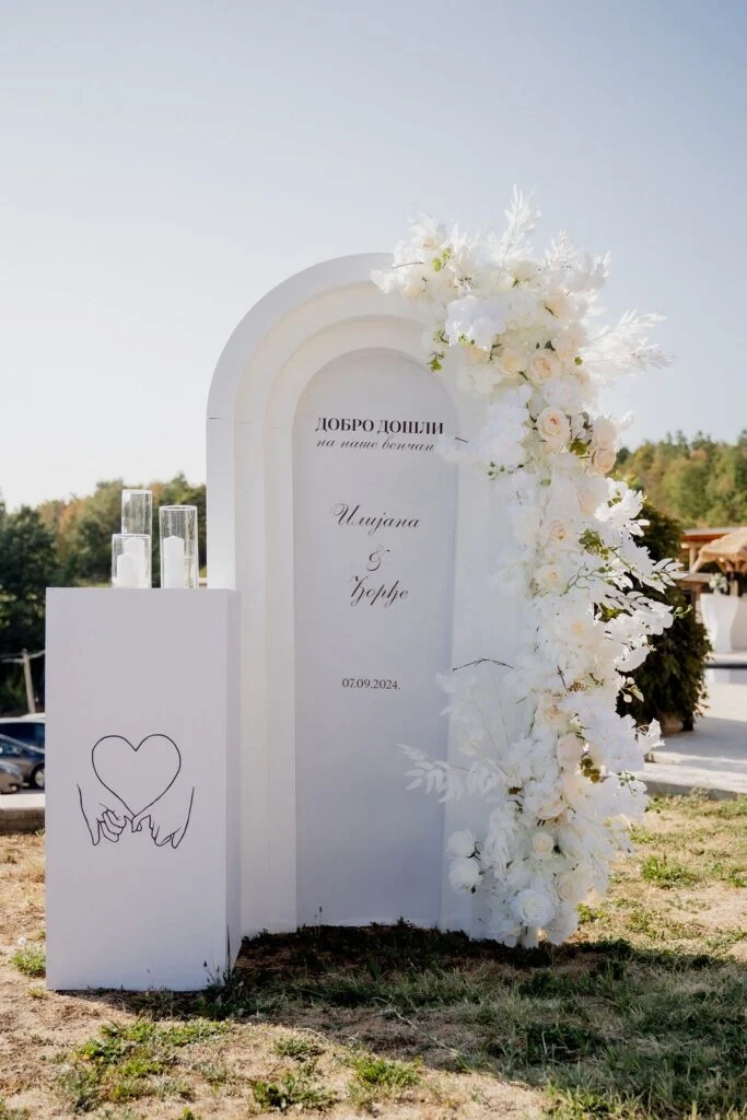 White welcome arch with flowers standing in the open field