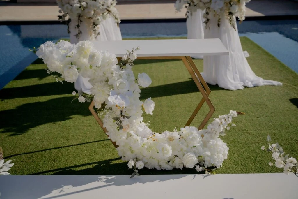 Ceremony arch of white flowers beside the swimming pool