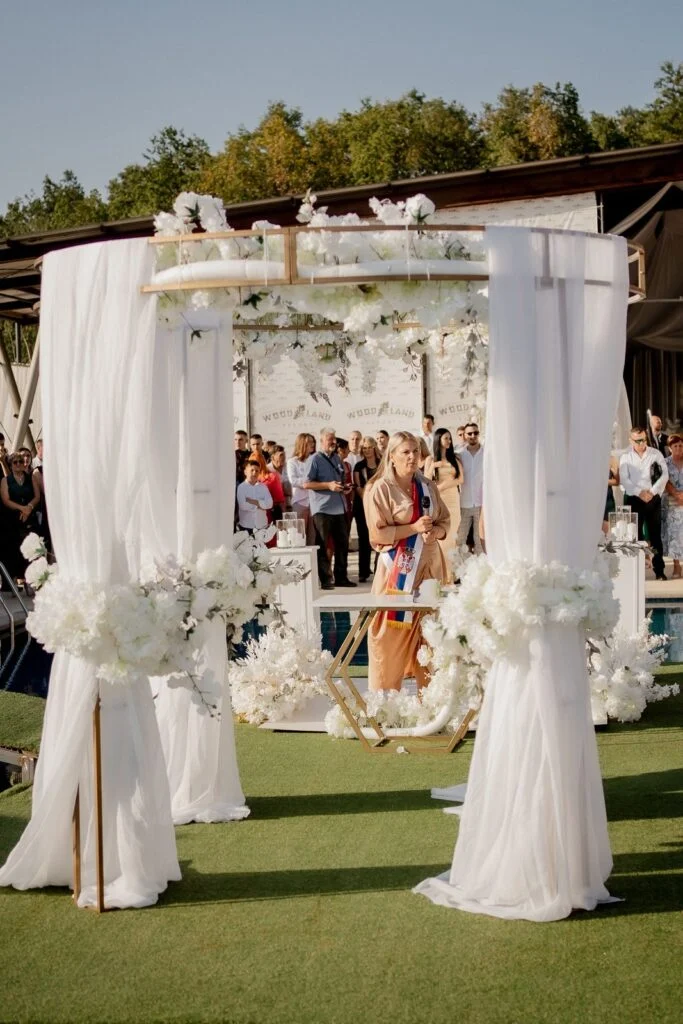 Guests gathered around the white ceremony arch by the pool