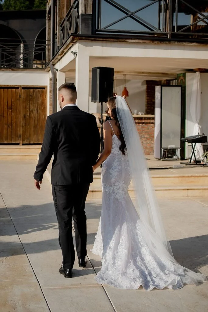 Bride and groom walking towards the ceremony, her train behind her