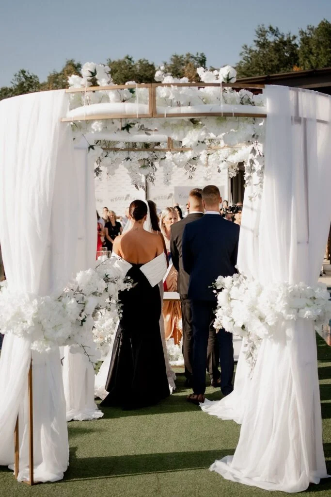 Bride and groom during the ceremony, white drapes on either side