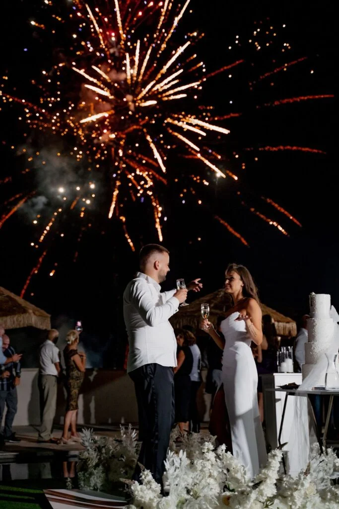 Fireworks bursting above the couple at the wedding cake