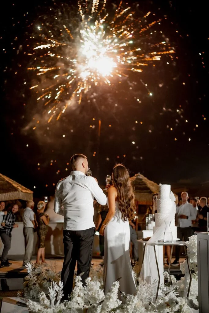 Bride and groom kissing beneath the fireworks