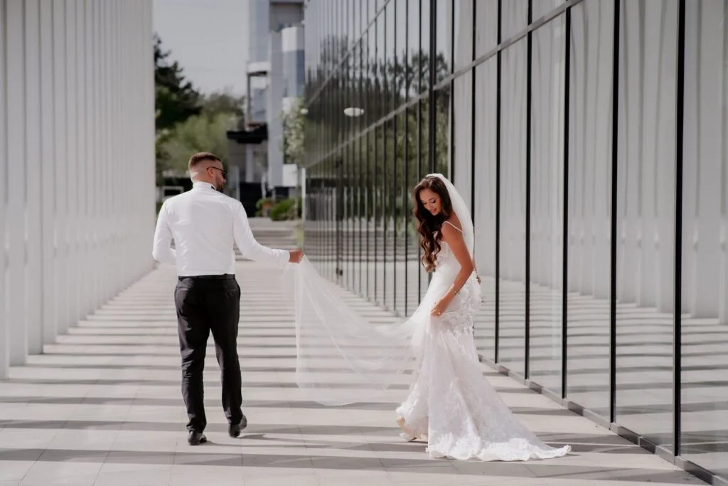 Bride and groom walking between white columns, her train trailing behind