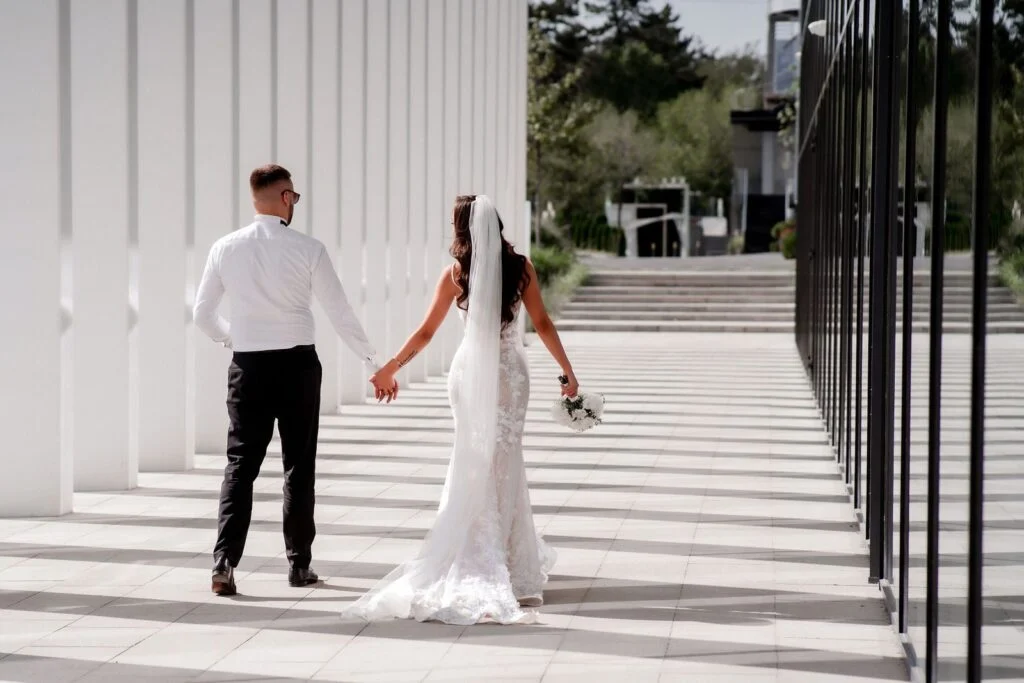 Bride and groom hand in hand in the white colonnade