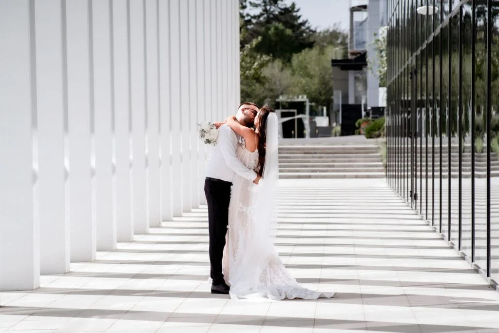 Bride and groom embracing in the white colonnade