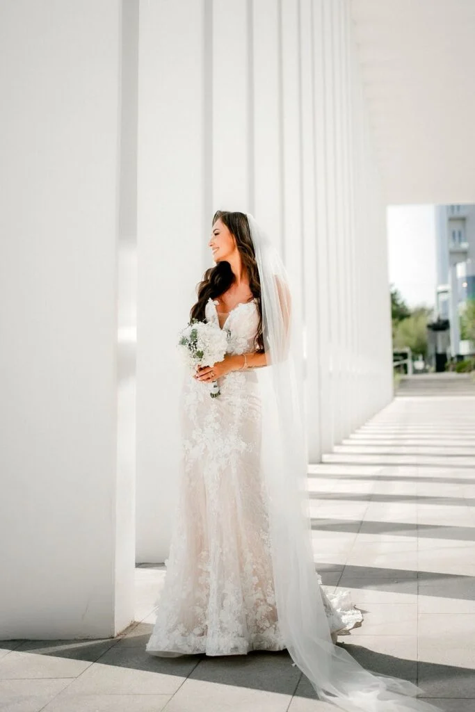 Bride standing in the light between two white columns