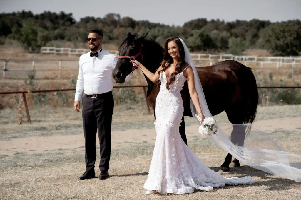Bride and groom beside a horse in the open field